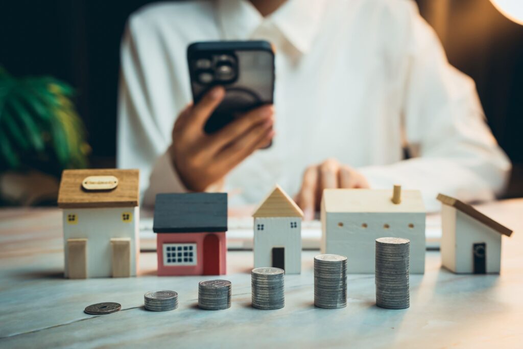 Hausbesitzer mit Miniaturhäusern und Münzen