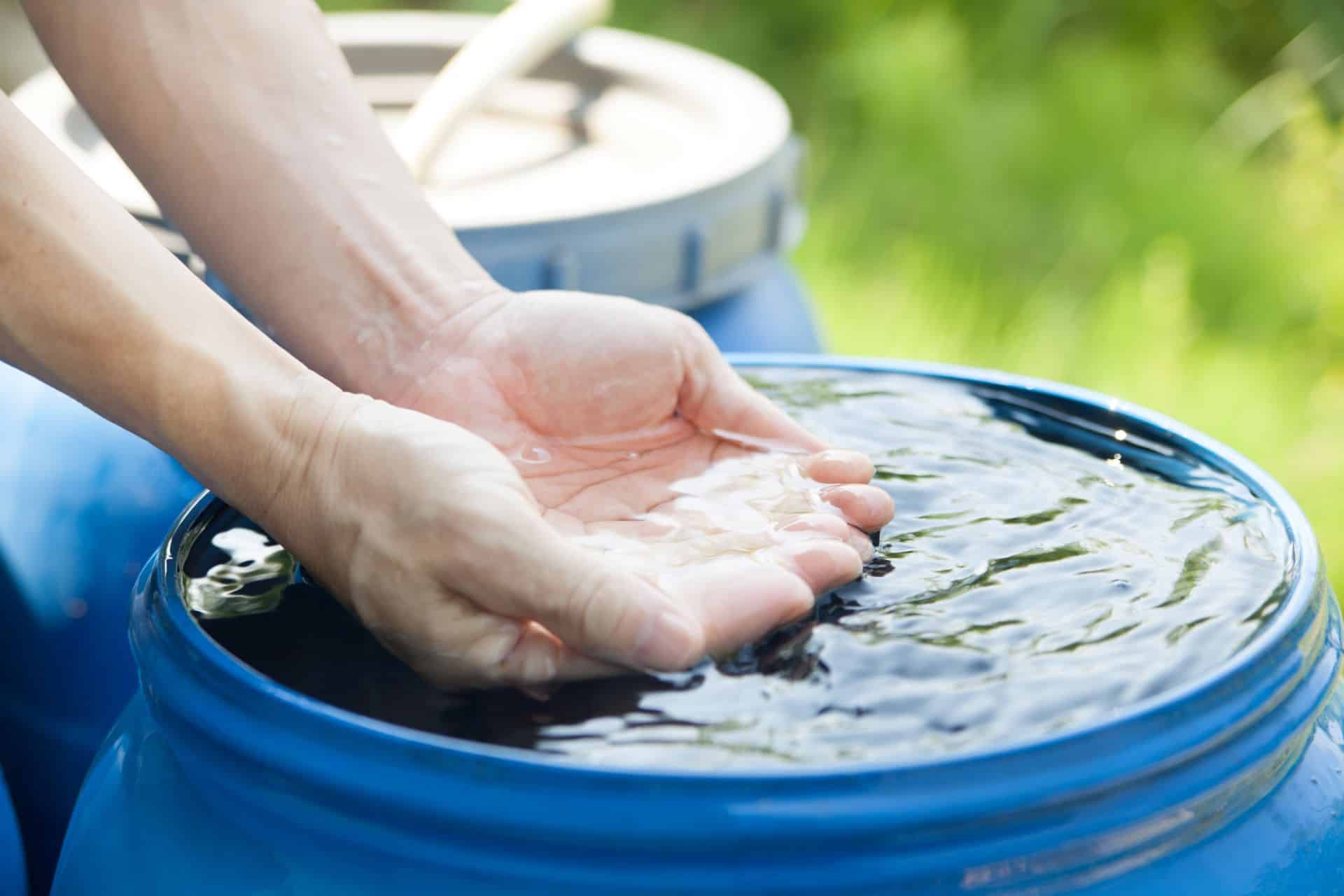 Hände über Wassertonne im Garten