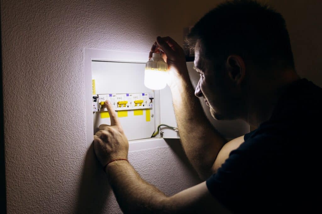 Mann kontrolliert Sicherung bei Stromausfall mit Notbeleuchtung | Taschenlampen